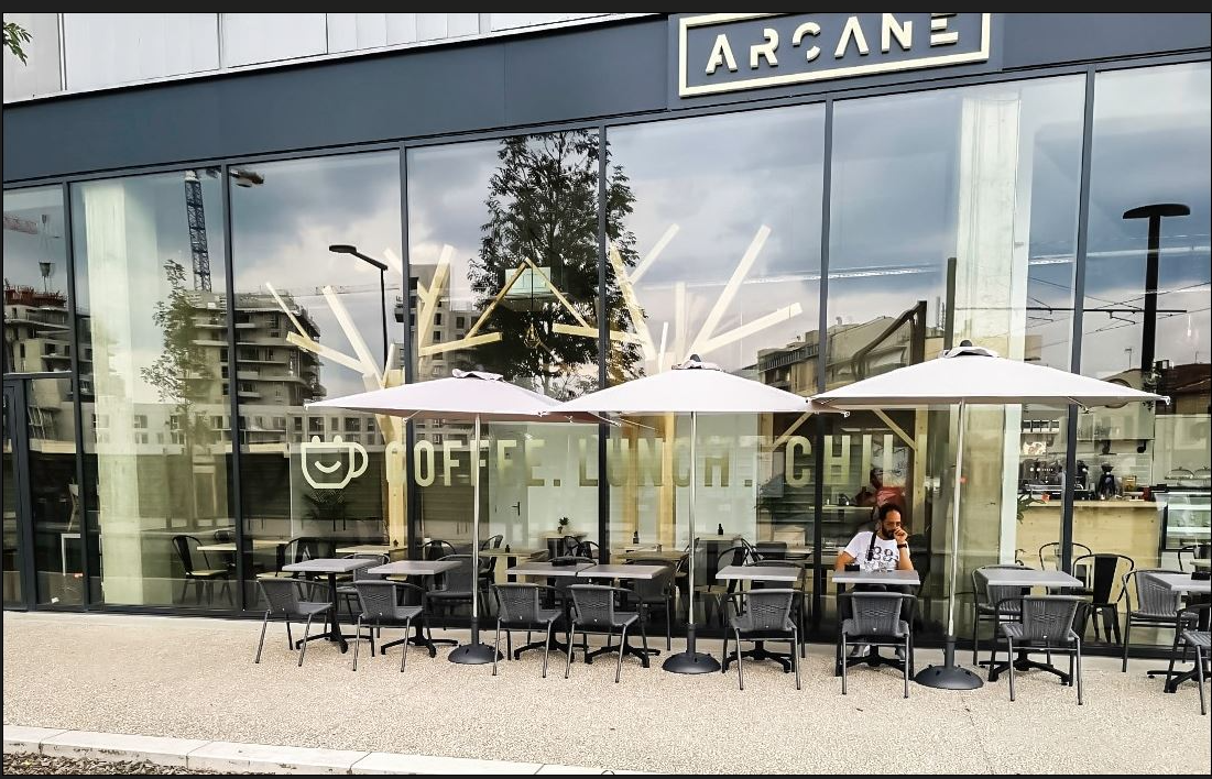 Façade vitrée et terrasse d'un espace de restauration, enseigne Arcane